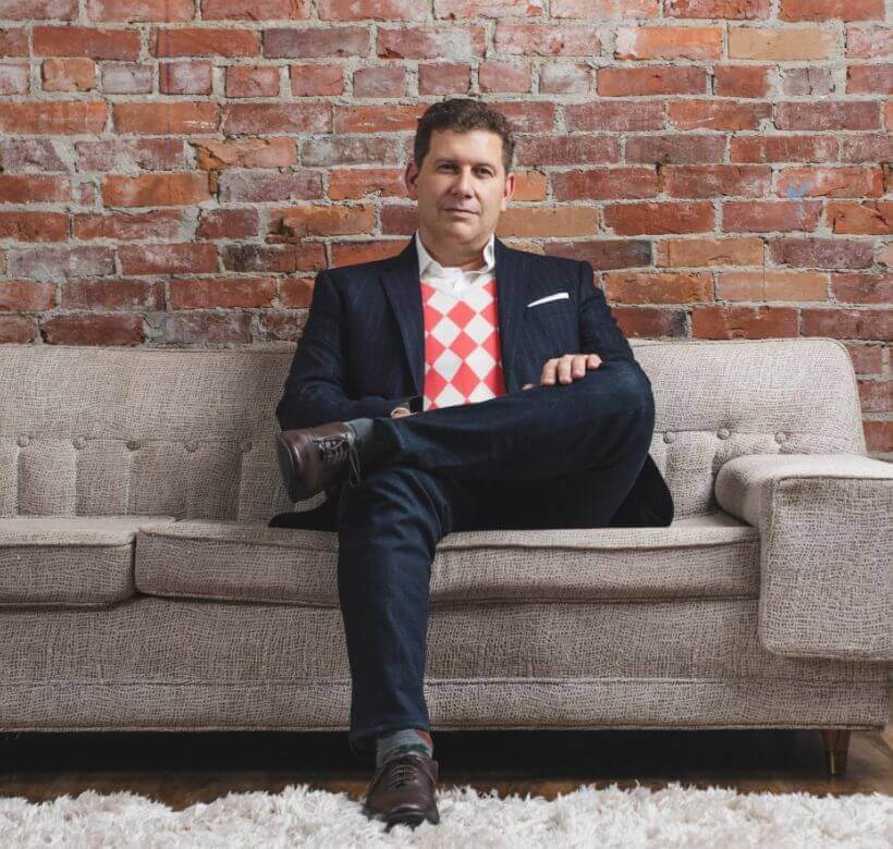 Dr. Gougoutas sitting on a couch in a suit