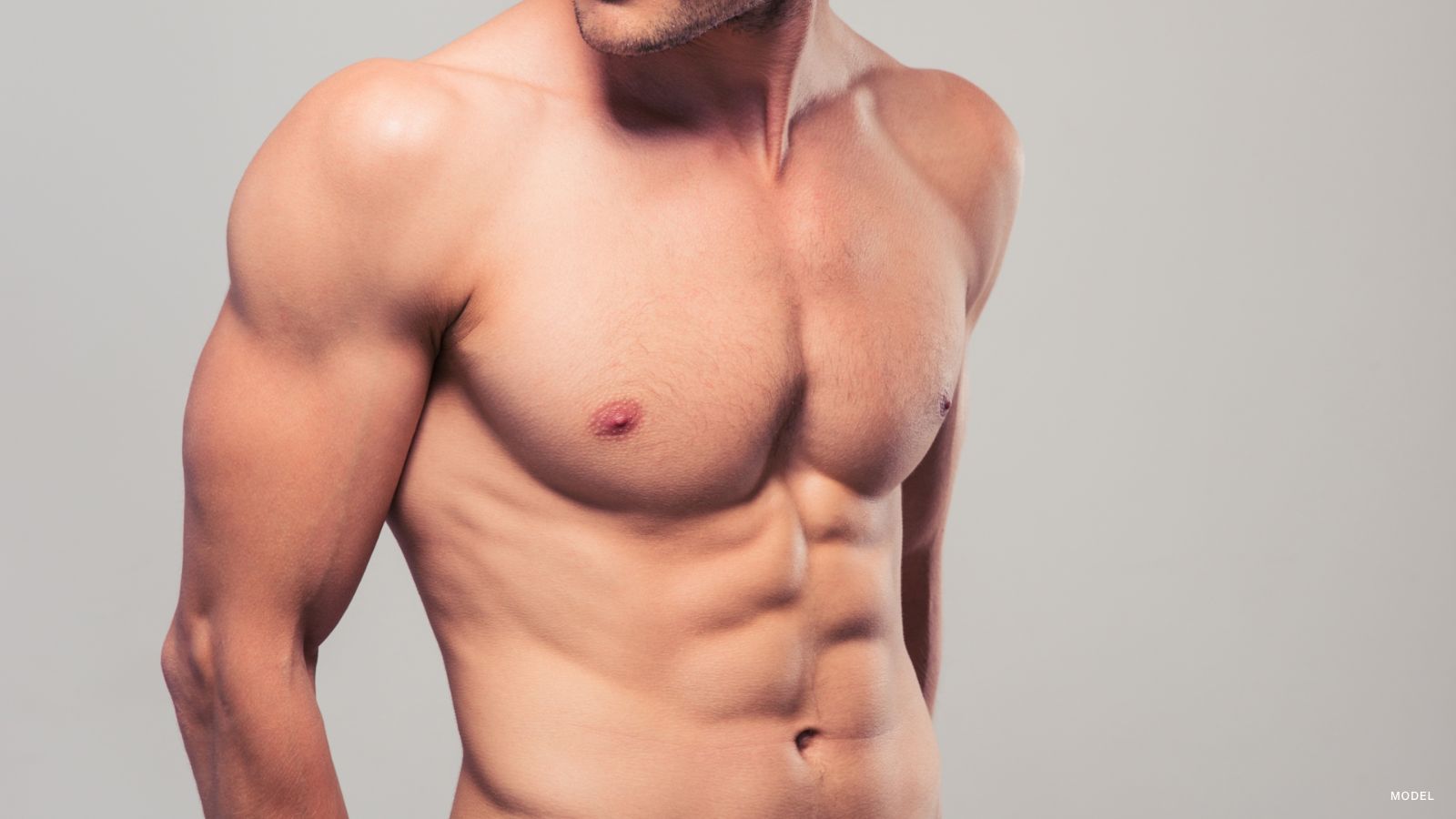a man's turso and fit body standing against a grey background